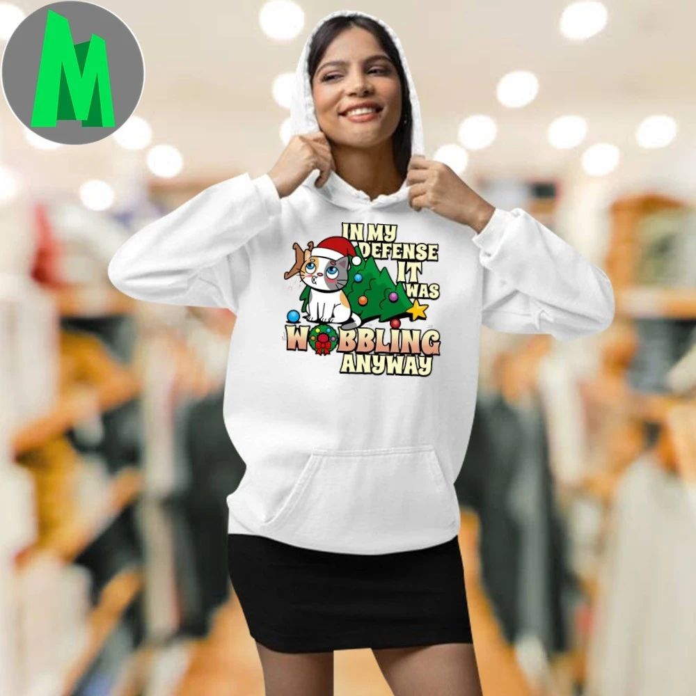 It Was Wobbling Anyway A cat wearing a Santa hat sits next to a fallen Christmas tree T-Shirt