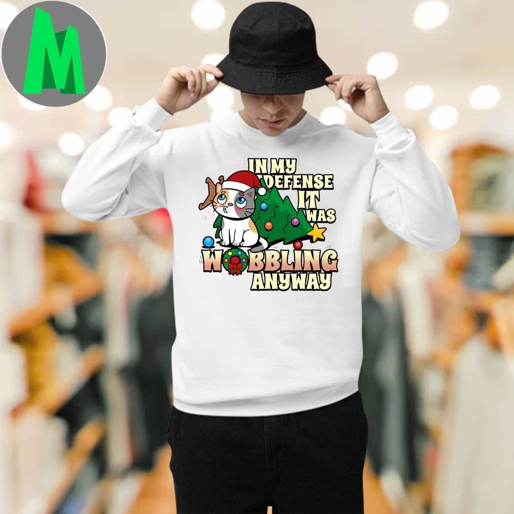 It Was Wobbling Anyway A cat wearing a Santa hat sits next to a fallen Christmas tree T-Shirt